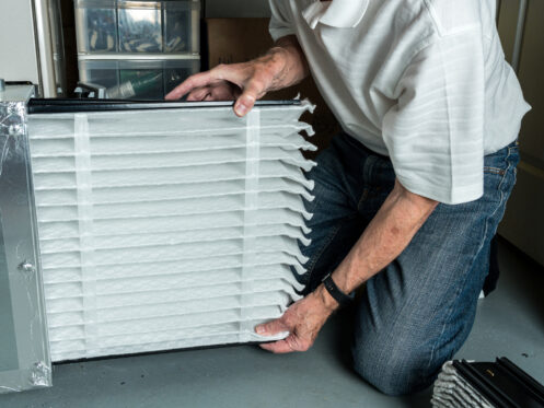 Homeowner inserting clean furnace filter